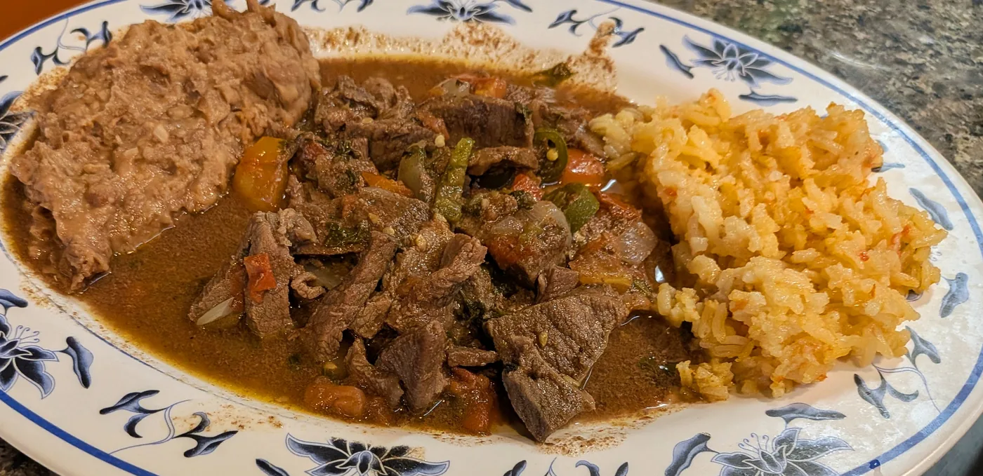 Bistec a la mexicana with rice and refried beans