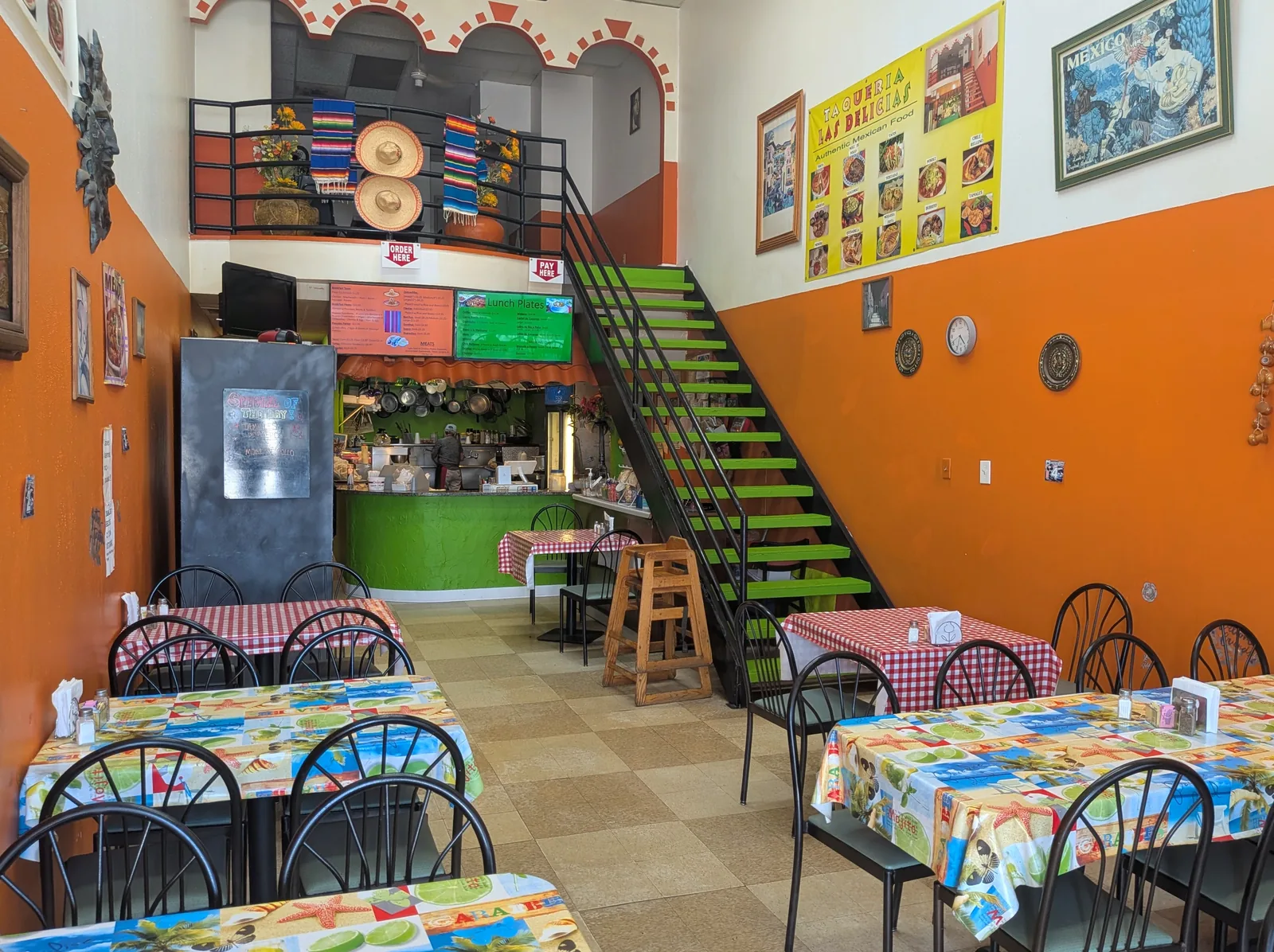 Dining room at Las Delicias Taqueria with orange walls and green staircase
