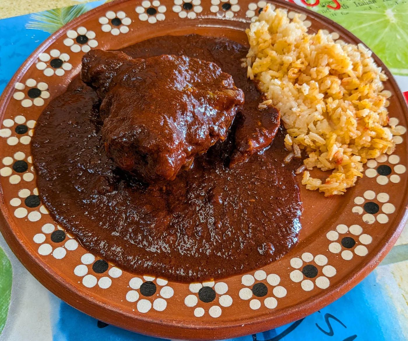 Chicken mole served with Mexican rice on a traditional clay plate